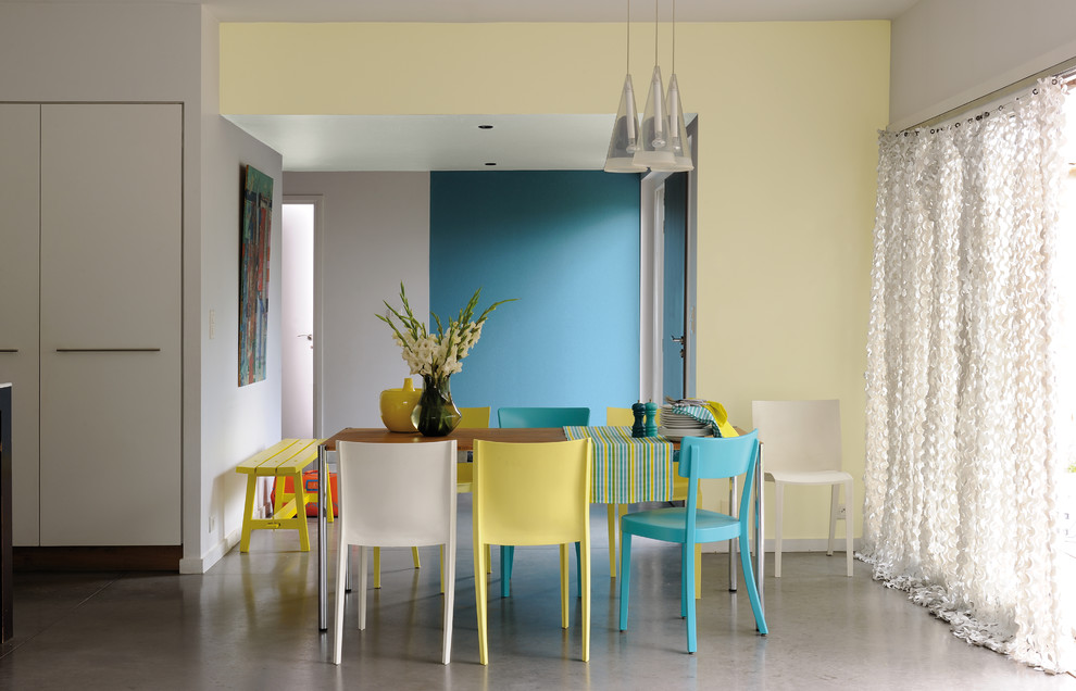 Design ideas for a contemporary dining room in Lyon with yellow walls and concrete floors.