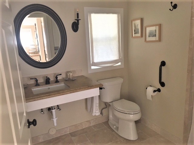 Inspiration for a mid-sized traditional 3/4 bathroom in Los Angeles with white cabinets, a curbless shower, a two-piece toilet, beige walls, travertine floors, an undermount sink, granite benchtops, beige floor and beige benchtops.