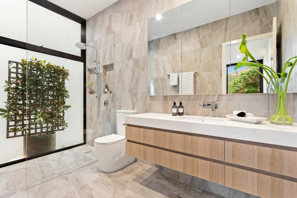 Design ideas for a contemporary master bathroom in Melbourne with flat-panel cabinets, light wood cabinets, a curbless shower, a two-piece toilet, beige tile, beige walls, an undermount sink, beige floor, an open shower, white benchtops, a niche and a floating vanity.