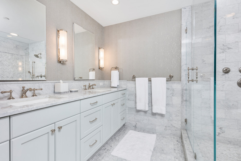 Classic bathroom in Boston with flat-panel cabinets, blue cabinets, a corner shower, white tiles, marble tiles, engineered stone worktops, a hinged door, double sinks and wallpapered walls.