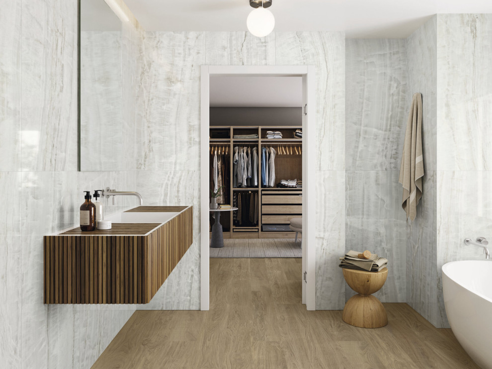 This is an example of a large contemporary bathroom in Sussex with dark wood cabinets, a freestanding bath, white tiles, marble tiles, white walls, wood-effect flooring, brown floors, a single sink and a floating vanity unit.