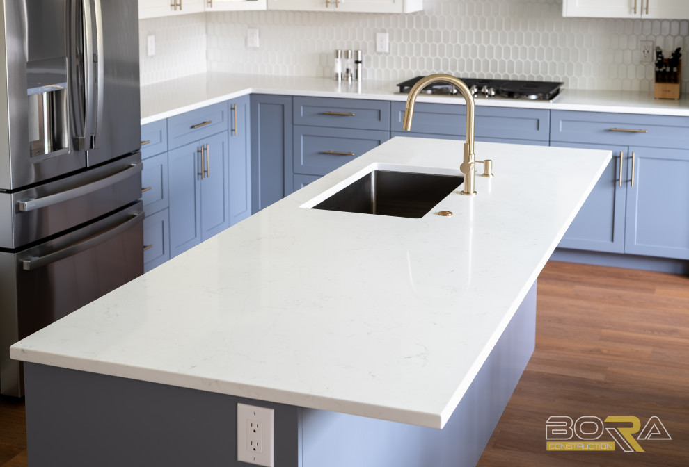 Inspiration for a large transitional l-shaped medium tone wood floor and brown floor eat-in kitchen remodel in Seattle with an undermount sink, shaker cabinets, blue cabinets, quartz countertops, white backsplash, ceramic backsplash, stainless steel appliances, an island and white countertops