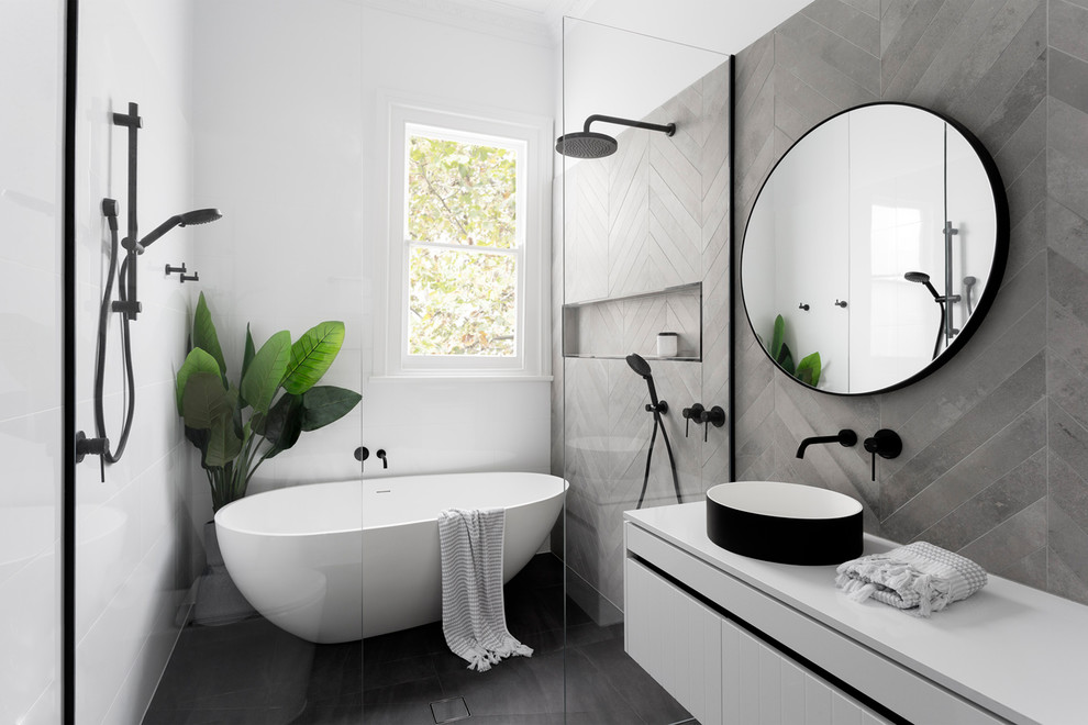 This is an example of a mid-sized contemporary master wet room bathroom in Melbourne with flat-panel cabinets, white cabinets, a freestanding tub, gray tile, white tile, a vessel sink, a wall-mount toilet, cement tile, engineered quartz benchtops and white benchtops.