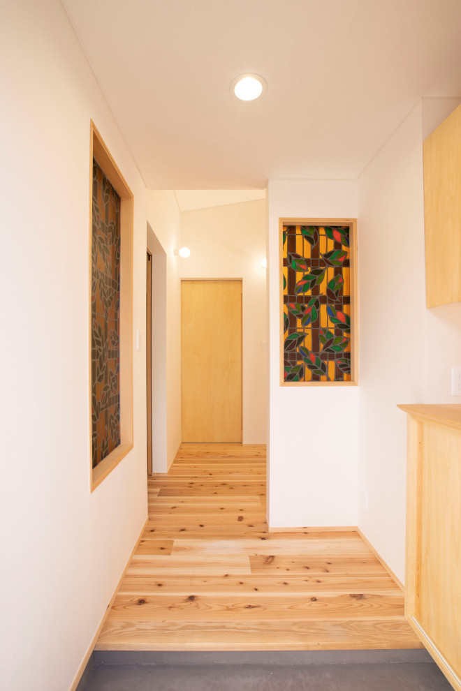Example of a small medium tone wood floor, brown floor, wallpaper ceiling and wallpaper entryway design in Tokyo