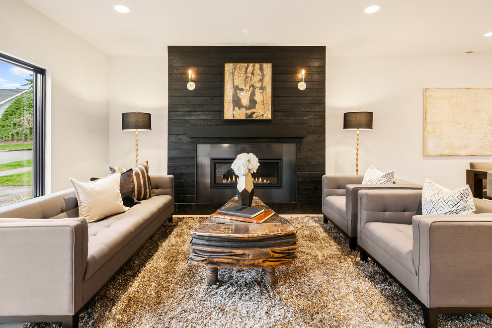 Photo of a contemporary living room in Seattle with light hardwood floors, a standard fireplace and a wood fireplace surround.