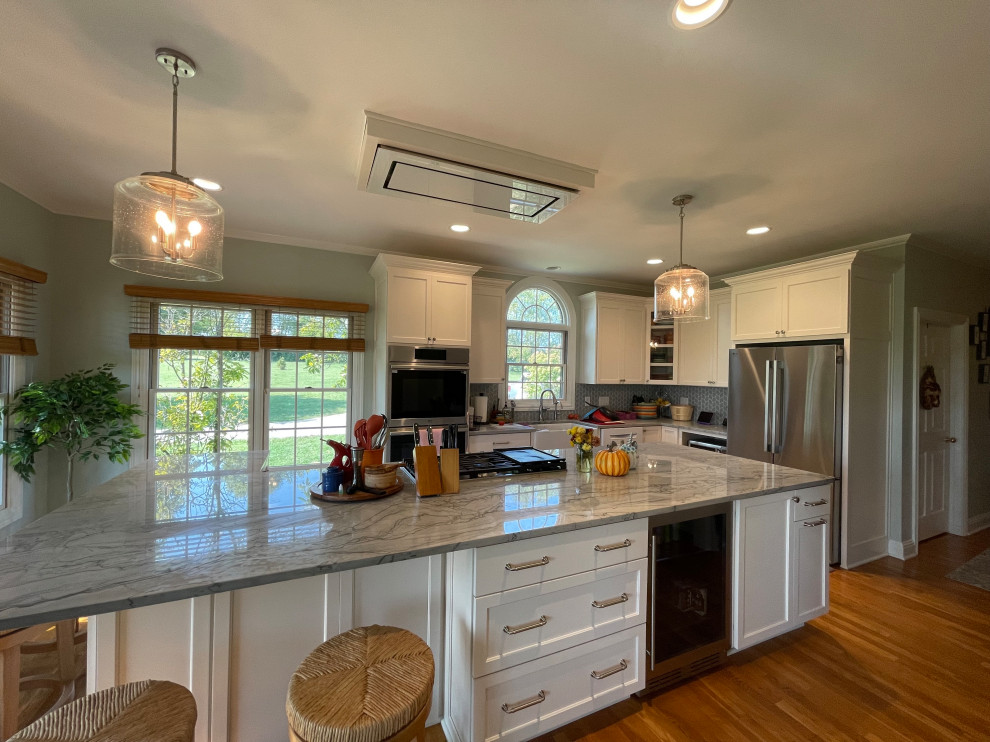 Example of a large transitional light wood floor and brown floor eat-in kitchen design with an undermount sink, shaker cabinets, white cabinets, quartzite countertops, green backsplash, marble backsplash, stainless steel appliances, an island and gray countertops