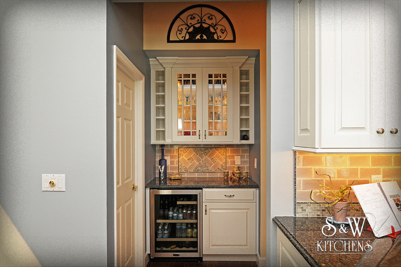 Example of a mid-sized transitional u-shaped dark wood floor open concept kitchen design in Orlando with a double-bowl sink, raised-panel cabinets, white cabinets, granite countertops, beige backsplash, subway tile backsplash and stainless steel appliances