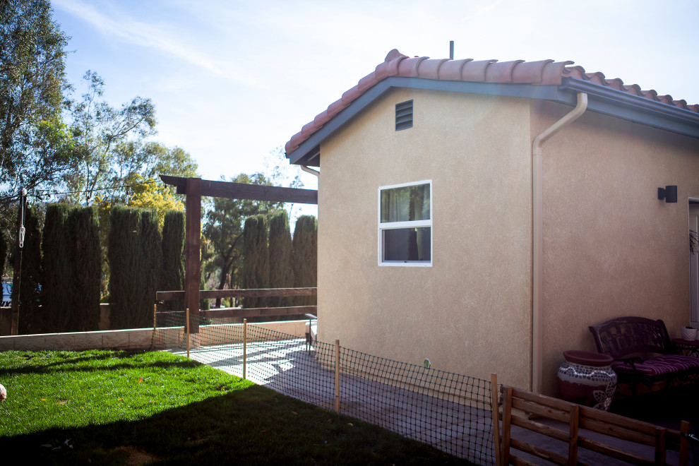 Стильный дизайн: маленький, одноэтажный, бежевый мини дом в стиле модернизм с облицовкой из цементной штукатурки, черепичной крышей и красной крышей для на участке и в саду - последний тренд