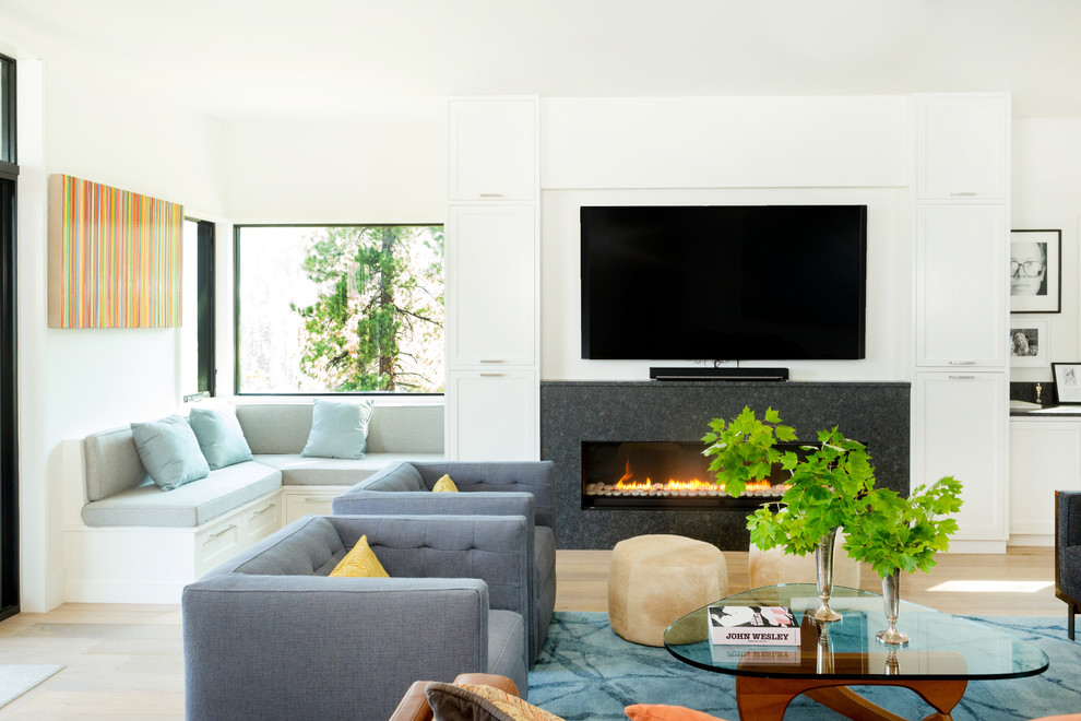 Inspiration for a contemporary living room in Sacramento with white walls, light hardwood floors, a ribbon fireplace, a wall-mounted tv and beige floor.