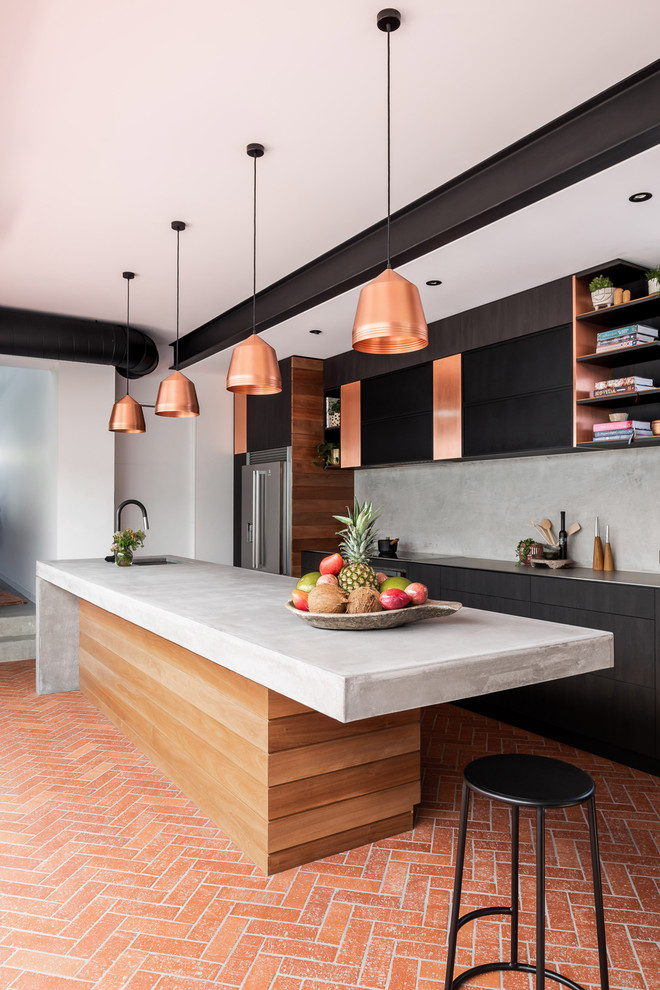 Photo of a large industrial galley separate kitchen in Perth with an undermount sink, flat-panel cabinets, dark wood cabinets, concrete benchtops, grey splashback, stainless steel appliances, brick floors, with island, red floor and grey benchtop.