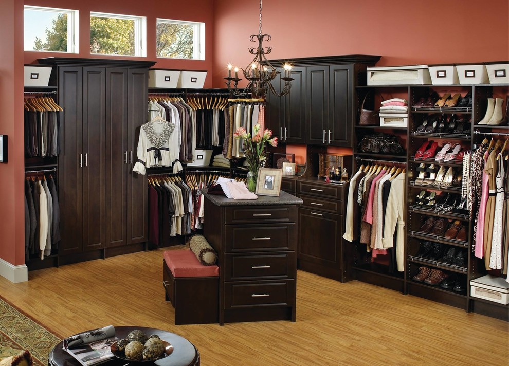 Inspiration for a large traditional gender-neutral dressing room in Other with raised-panel cabinets, black cabinets, light hardwood floors and brown floor.