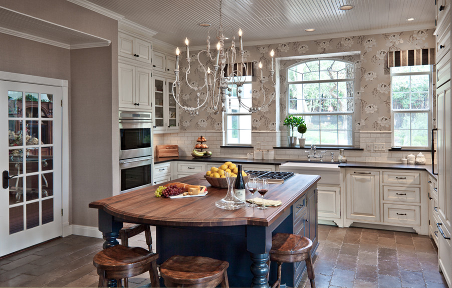 Inspiration for a traditional kitchen in Austin with a farmhouse sink, beaded inset cabinets, distressed cabinets, wood benchtops, white splashback, subway tile splashback, stainless steel appliances, marble floors and with island.