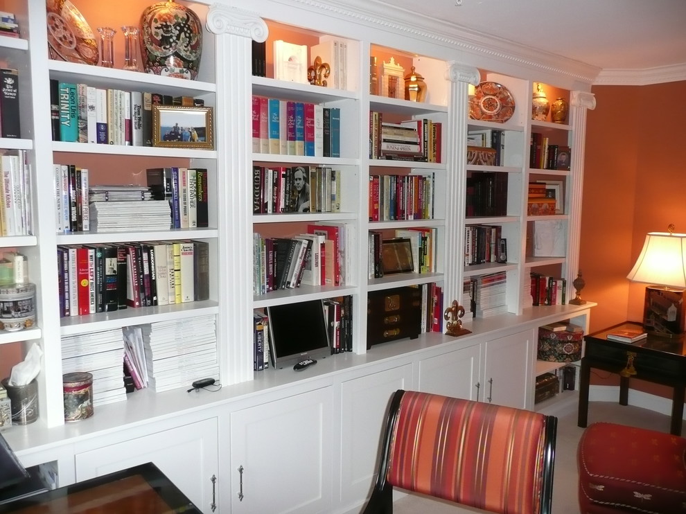 Photo of a mid-sized traditional home office in Boston with a library, orange walls, carpet, no fireplace, a freestanding desk and beige floor.