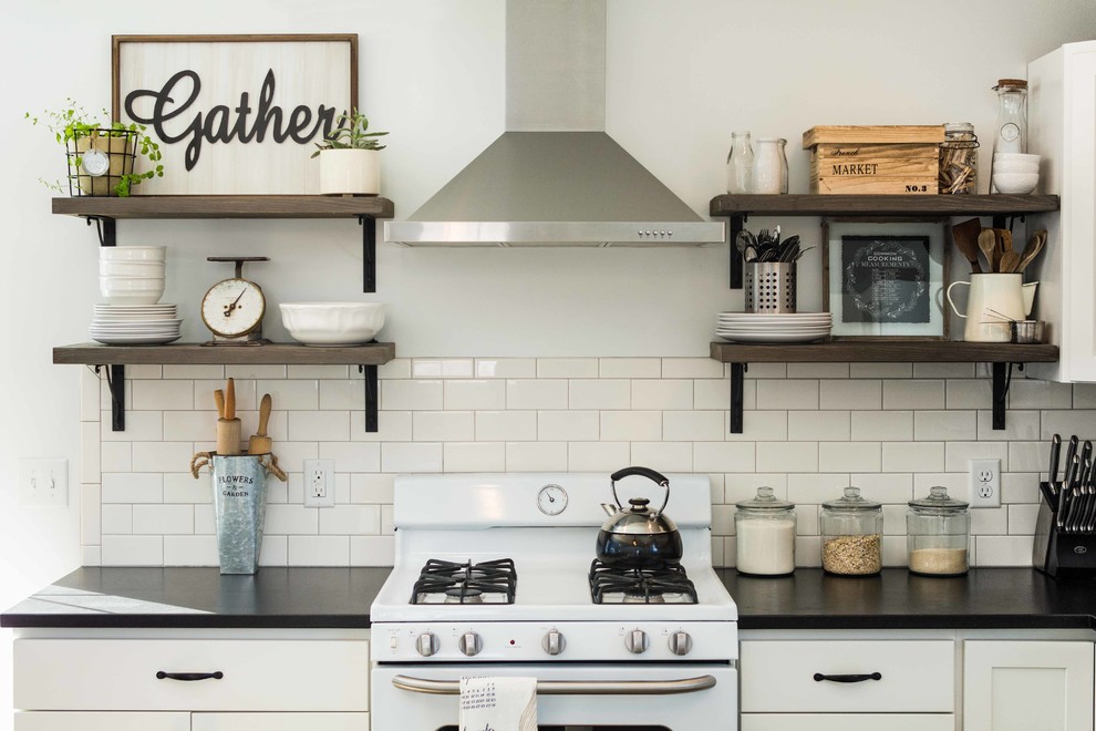 Design ideas for a country l-shaped eat-in kitchen in Portland Maine with a farmhouse sink, shaker cabinets, white cabinets, granite benchtops, white splashback, subway tile splashback, white appliances, vinyl floors and with island.