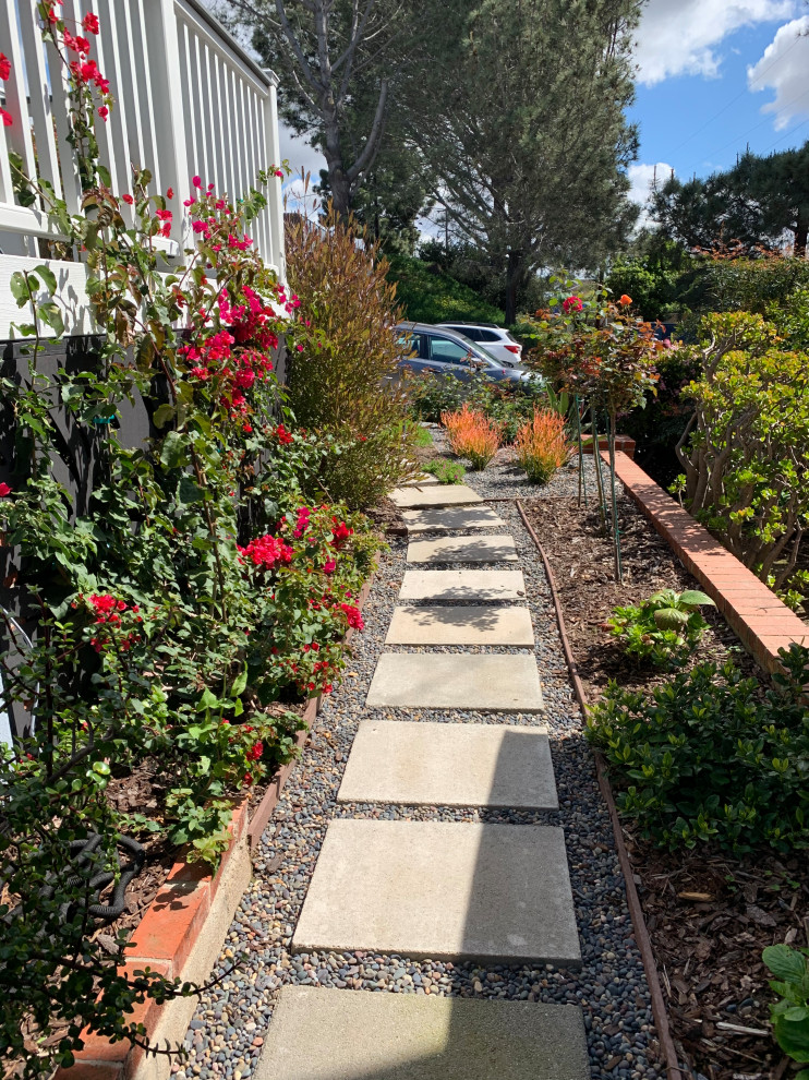 This is an example of a small beach style side yard full sun xeriscape in San Diego with with path and concrete pavers.