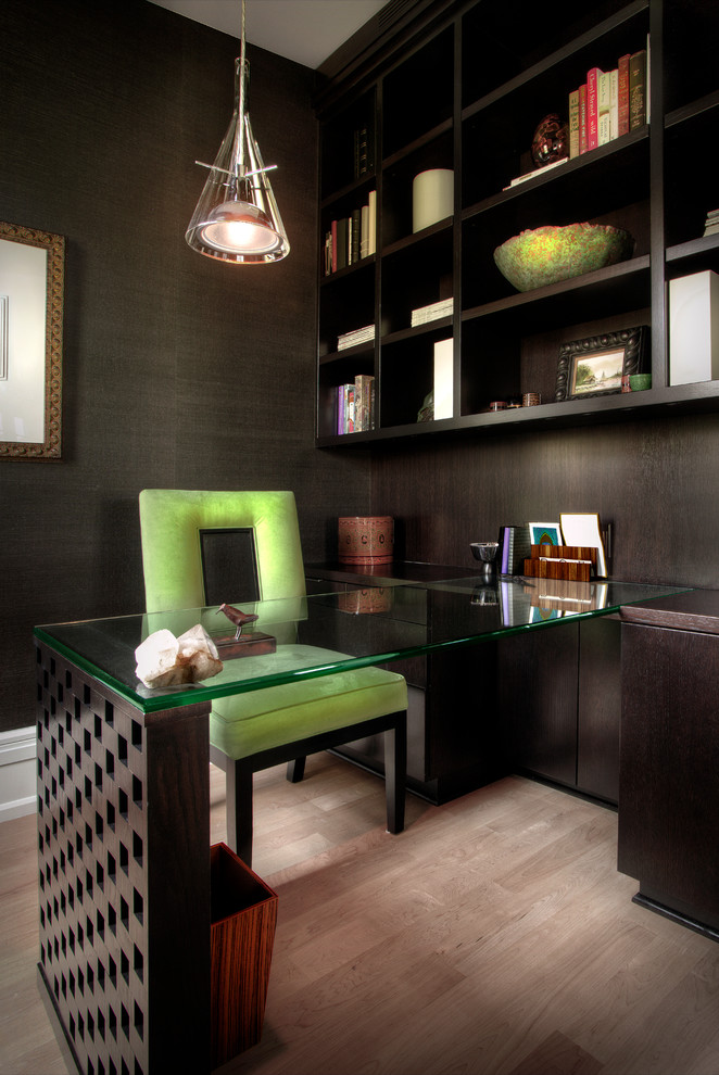 This is an example of a large contemporary home office in Detroit with a library, black walls, light hardwood floors, no fireplace and a freestanding desk.