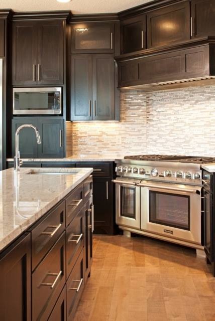 Large transitional l-shaped light wood floor enclosed kitchen photo in Minneapolis with an undermount sink, shaker cabinets, dark wood cabinets, marble countertops, gray backsplash, matchstick tile backsplash, stainless steel appliances and an island