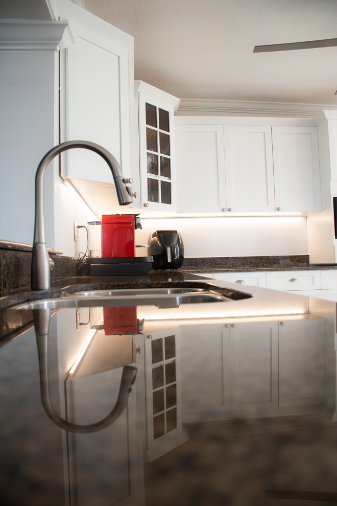 Eat-in kitchen - mid-sized transitional eat-in kitchen idea in Miami with a single-bowl sink, shaker cabinets, white cabinets, granite countertops, black backsplash, granite backsplash, stainless steel appliances, a peninsula and black countertops