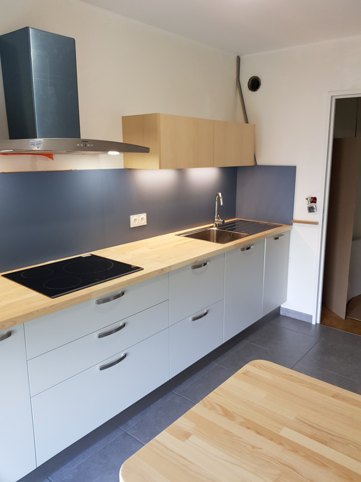 Mid-sized traditional galley separate kitchen in Angers with a single-bowl sink, beaded inset cabinets, light wood cabinets, wood benchtops, blue splashback, timber splashback, panelled appliances, ceramic floors and a peninsula.