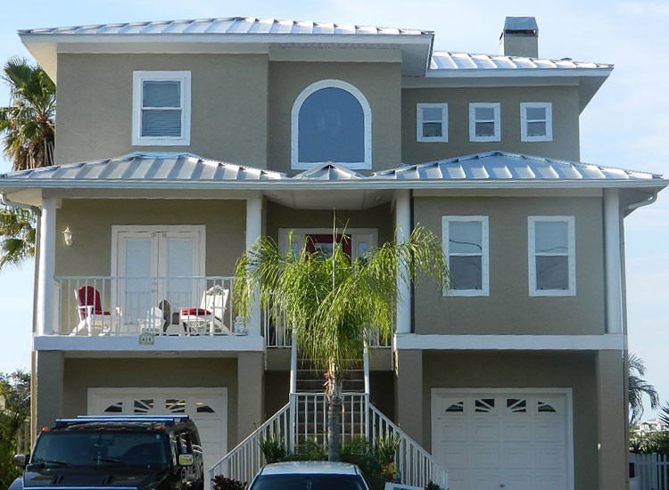 This is an example of a large beach style three-storey stucco beige exterior in Tampa with a hip roof.