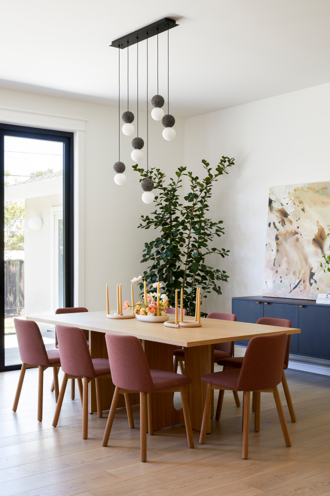 This is an example of a small scandinavian open plan dining in San Francisco with white walls, light hardwood floors, no fireplace and brown floor.