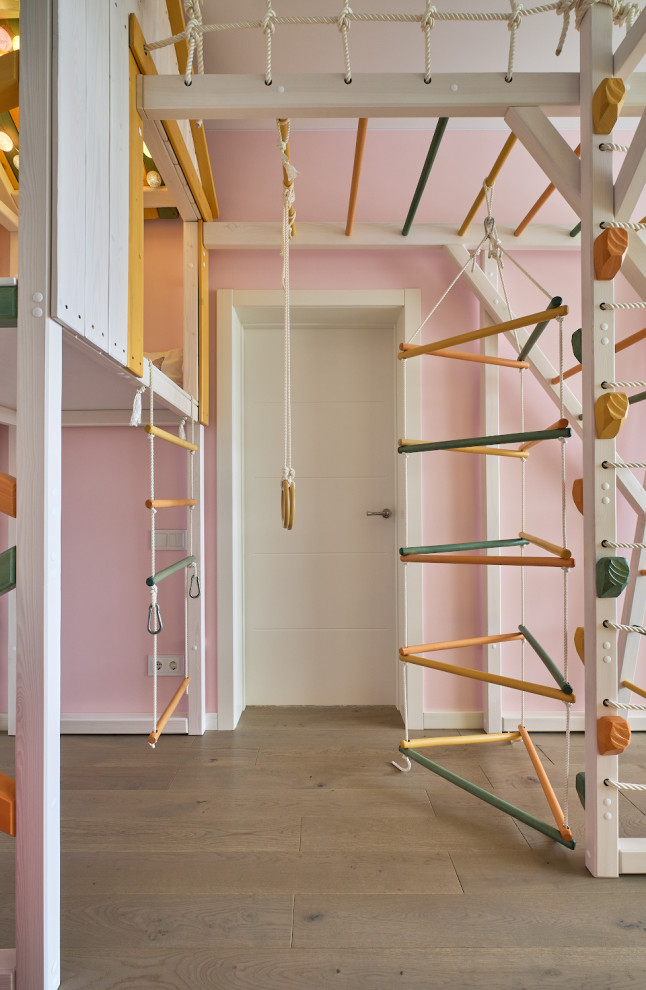 This is an example of a medium sized contemporary kids' bedroom for girls in Moscow with pink walls, medium hardwood flooring and beige floors.