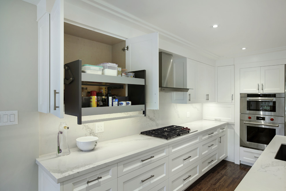 This is an example of a transitional eat-in kitchen in Toronto with an undermount sink, shaker cabinets, white cabinets, stainless steel appliances, medium hardwood floors and with island.
