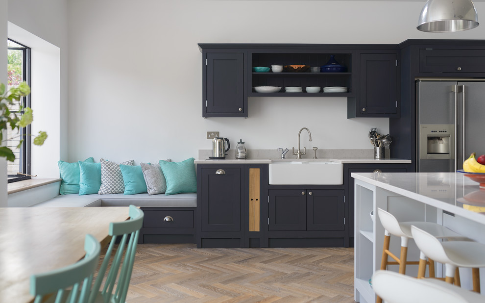 This is an example of a mid-sized transitional eat-in kitchen in London with shaker cabinets, dark wood cabinets, quartzite benchtops, with island, a farmhouse sink and brown floor.