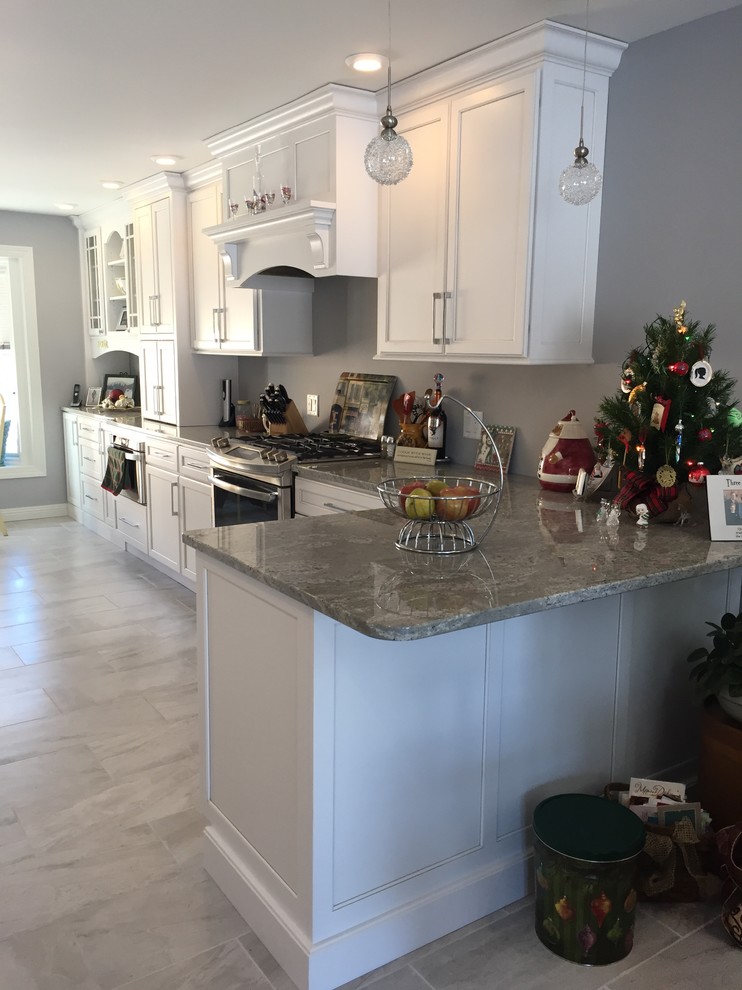 Example of a large transitional l-shaped porcelain tile and gray floor eat-in kitchen design with an undermount sink, shaker cabinets, white cabinets, granite countertops, stainless steel appliances and no island
