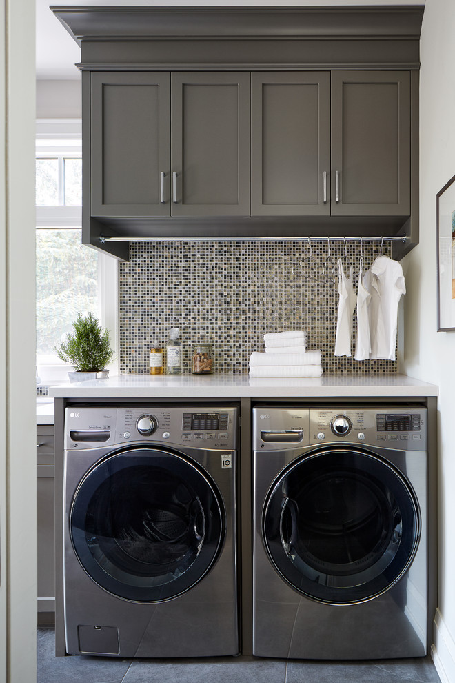 This is an example of a large contemporary single-wall utility room in Toronto with an undermount sink, shaker cabinets, grey cabinets, quartz benchtops, grey walls, porcelain floors and a side-by-side washer and dryer.