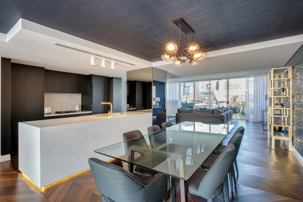 This is an example of a large contemporary galley eat-in kitchen in Sydney with an undermount sink, flat-panel cabinets, dark wood cabinets, white splashback, panelled appliances, medium hardwood floors, with island, brown floor and white benchtop.