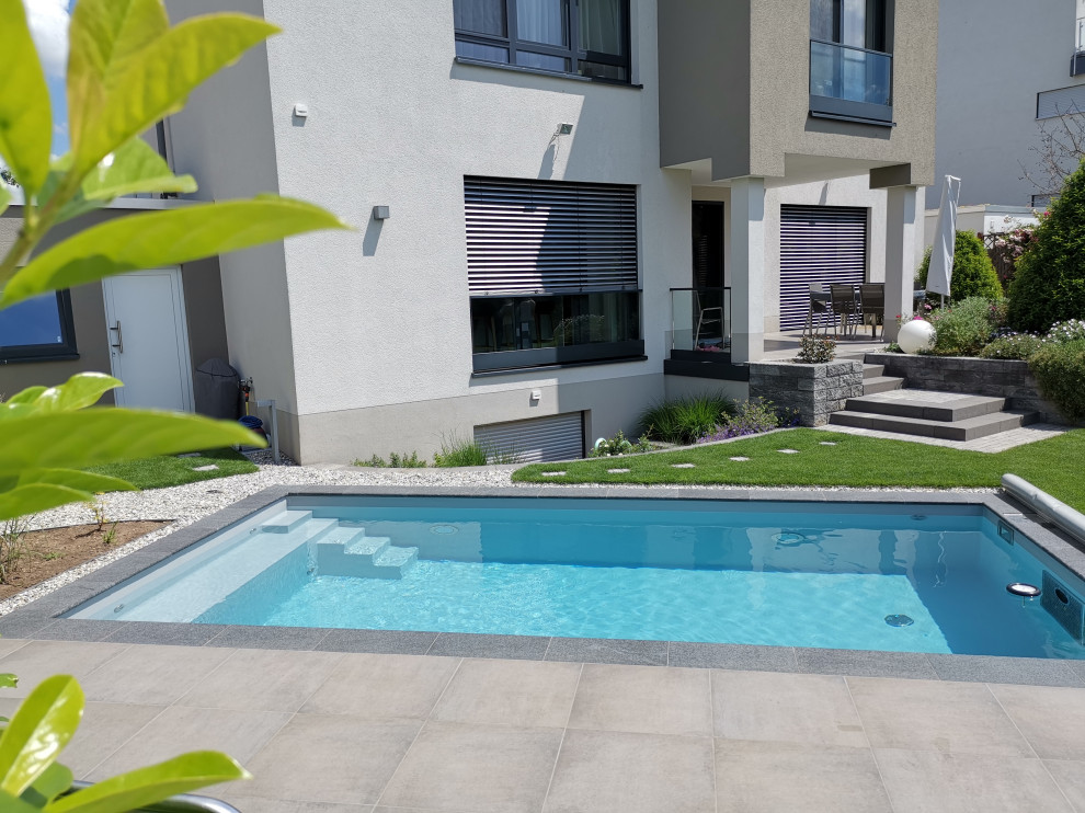 Inspiration for a mid-sized modern side yard rectangular pool in Frankfurt with natural stone pavers.