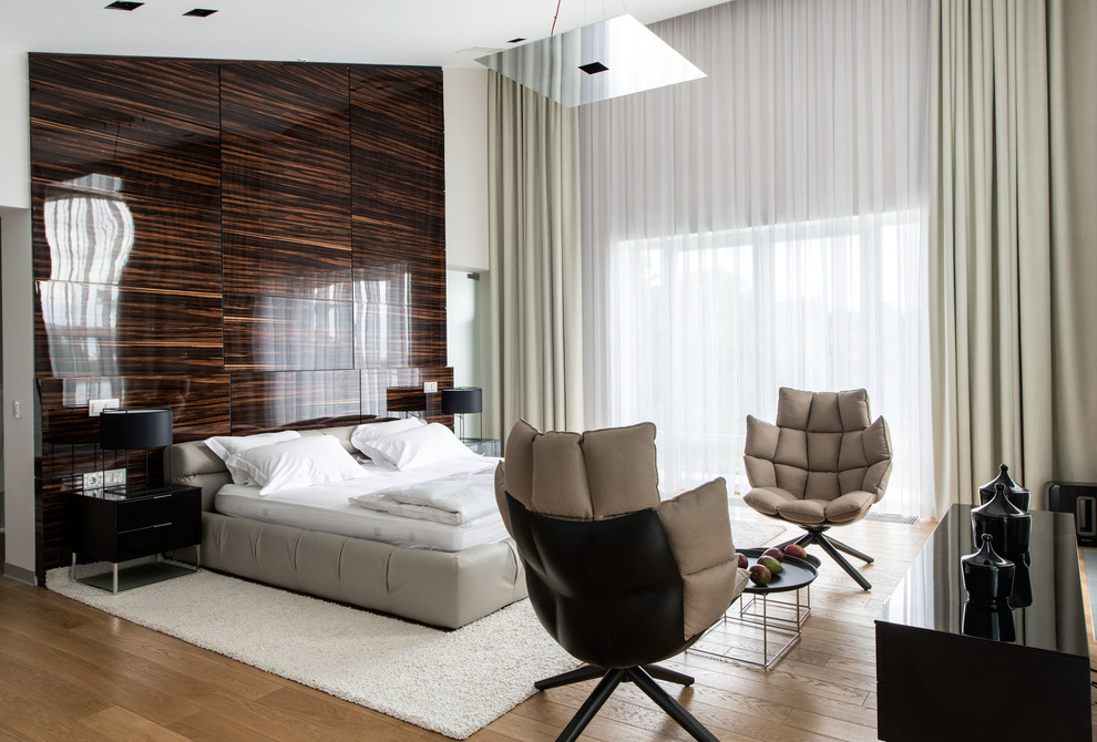 This is an example of a large contemporary master bedroom in Moscow with white walls and light hardwood floors.