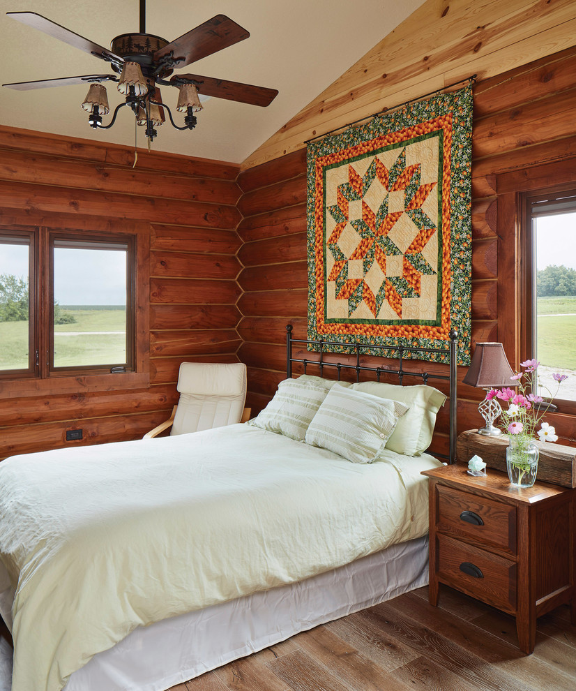 This is an example of a country guest bedroom in Other with brown walls, medium hardwood floors and brown floor.
