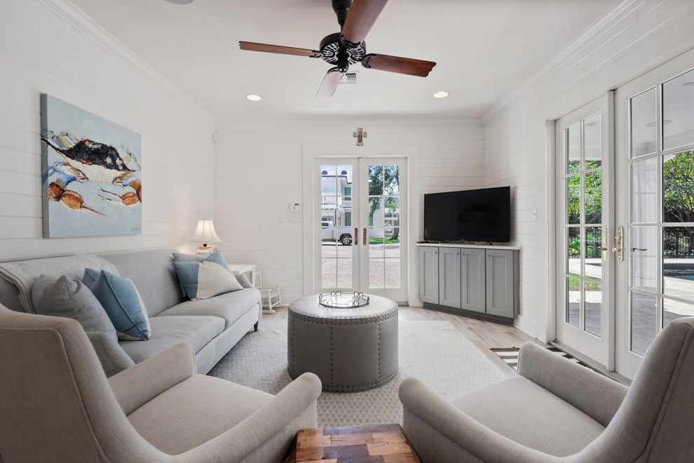 Example of a small french country open concept porcelain tile, beige floor and wood wall living room design in New Orleans with white walls and a corner tv