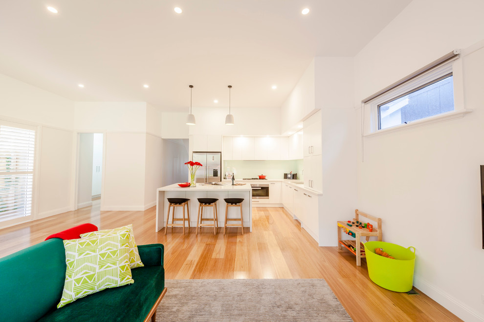 Photo of a large contemporary open concept living room in Melbourne with white walls, medium hardwood floors and a wall-mounted tv.