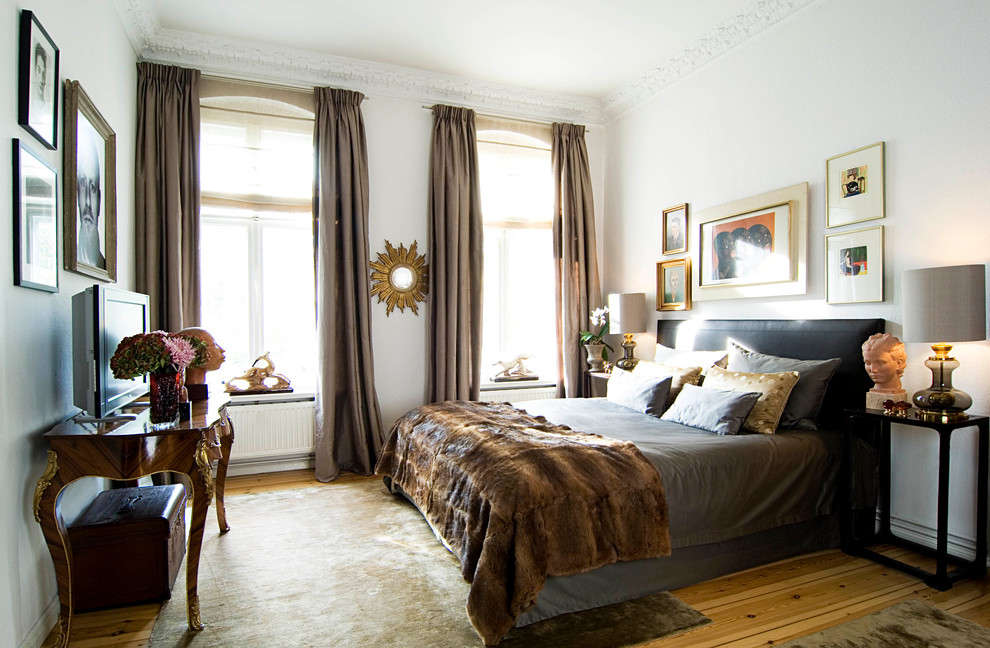 This is an example of a mid-sized eclectic master bedroom in Berlin with white walls, medium hardwood floors and no fireplace.