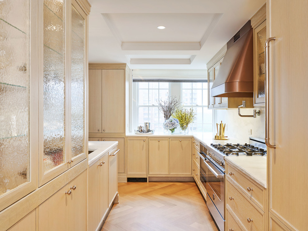 Contemporary l-shaped kitchen in New York with recessed-panel cabinets, light wood cabinets, white splashback, stainless steel appliances, light hardwood floors, beige floor and white benchtop.