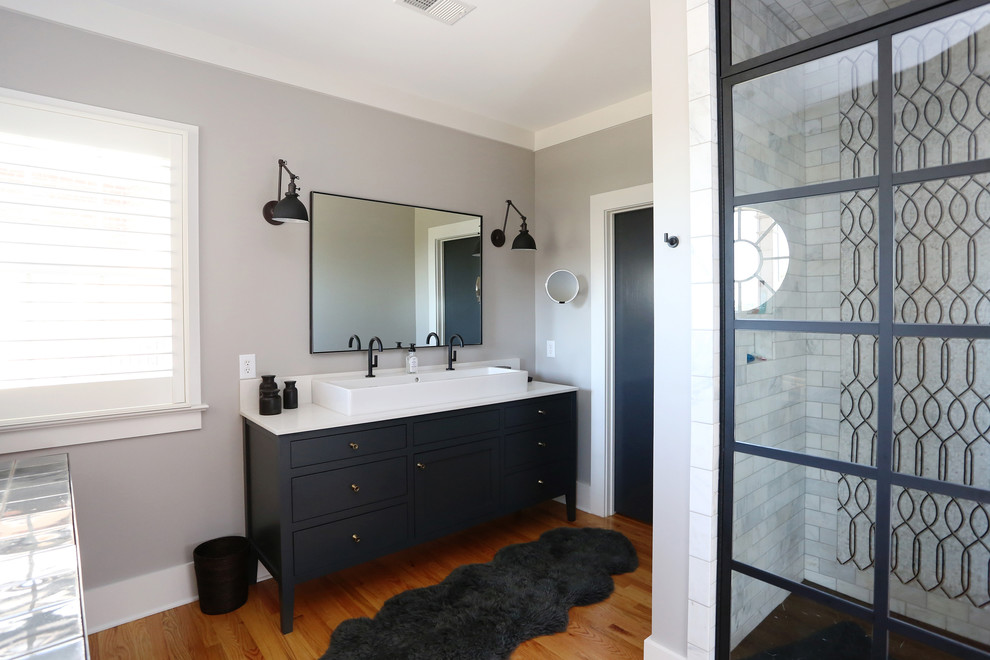 Design ideas for a mid-sized industrial master bathroom in Raleigh with recessed-panel cabinets, black cabinets, an alcove shower, black and white tile, subway tile, grey walls, medium hardwood floors, a vessel sink, engineered quartz benchtops, a two-piece toilet, orange floor, a hinged shower door and white benchtops.
