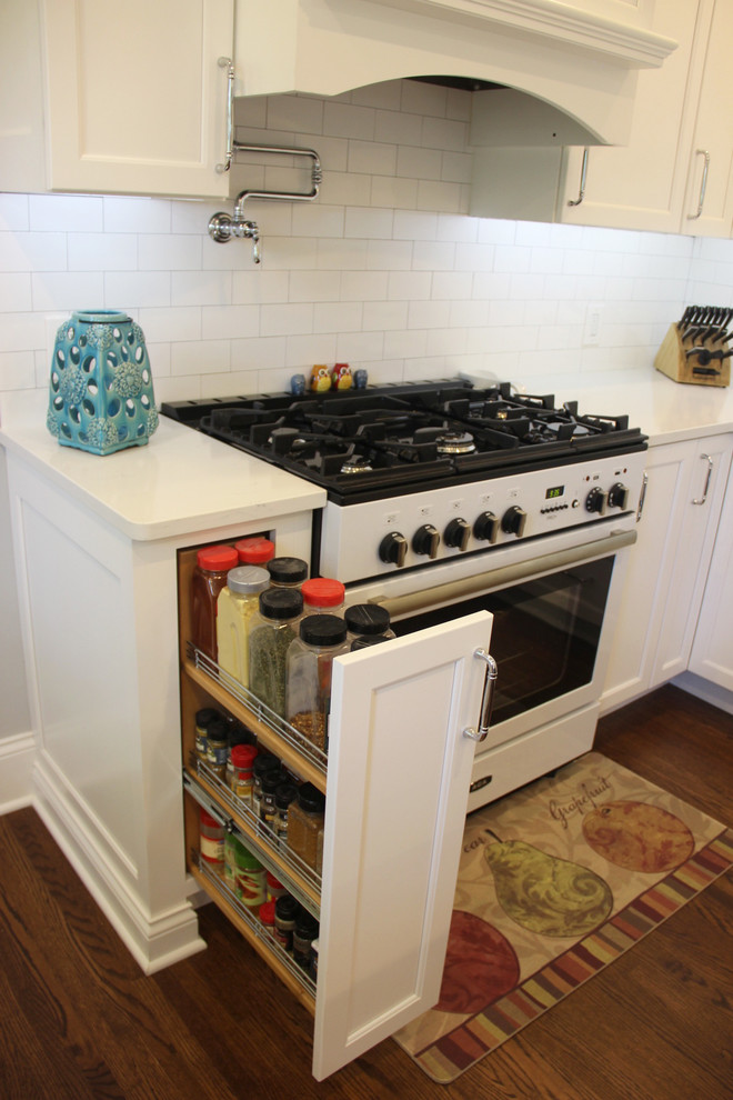 Mid-sized transitional u-shaped medium tone wood floor and brown floor eat-in kitchen photo with a farmhouse sink, shaker cabinets, white cabinets, quartz countertops, white backsplash, subway tile backsplash, white appliances and an island