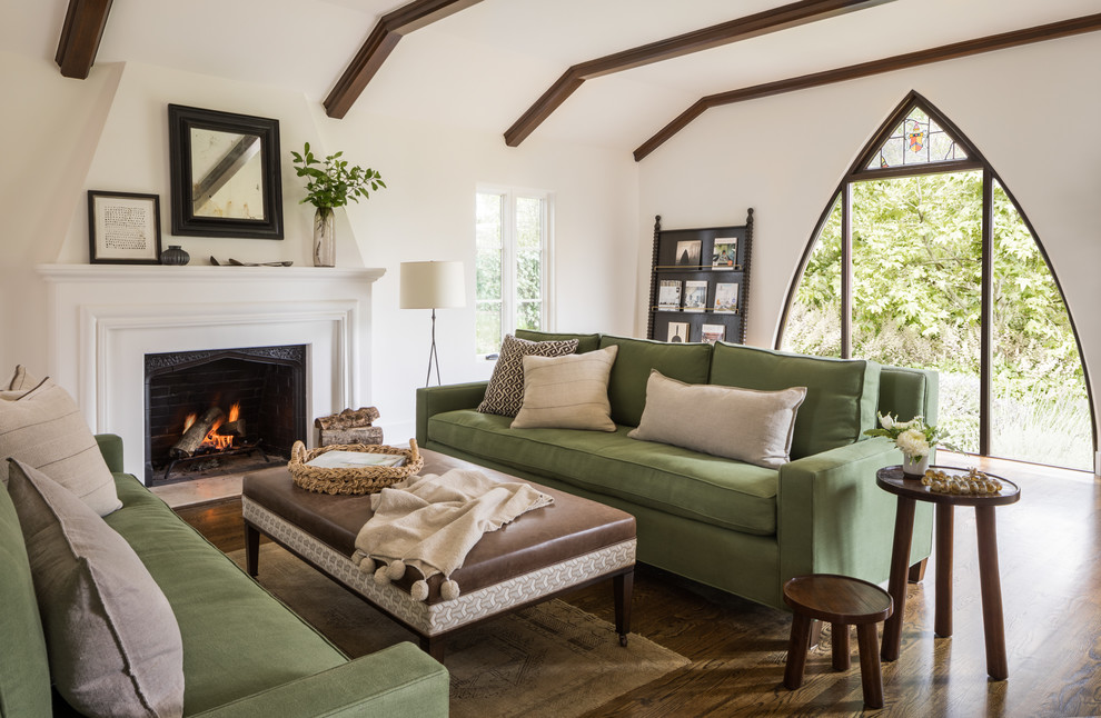 Design ideas for a mediterranean open concept living room in San Francisco with white walls, dark hardwood floors, a standard fireplace, a plaster fireplace surround, no tv and brown floor.