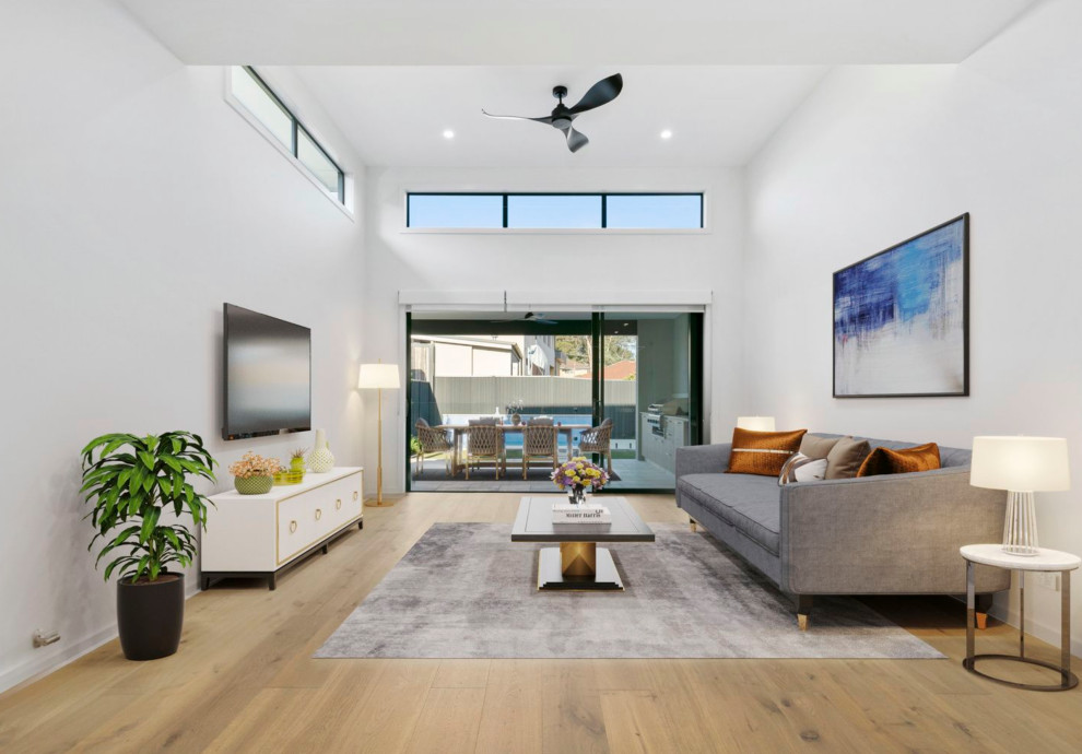 Medium sized modern open plan games room in Sydney with white walls, medium hardwood flooring, a wall mounted tv and brown floors.