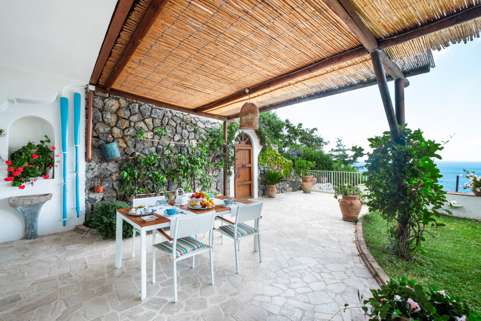 Ispirazione per un grande patio o portico mediterraneo davanti casa con pavimentazioni in pietra naturale e una pergola
