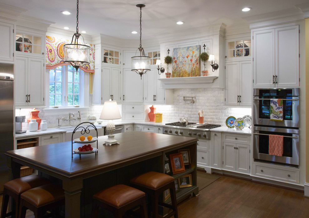 Eat-in kitchen - large transitional l-shaped dark wood floor and brown floor eat-in kitchen idea with a farmhouse sink, white cabinets, marble countertops, multicolored backsplash, marble backsplash, stainless steel appliances, an island and beaded inset cabinets