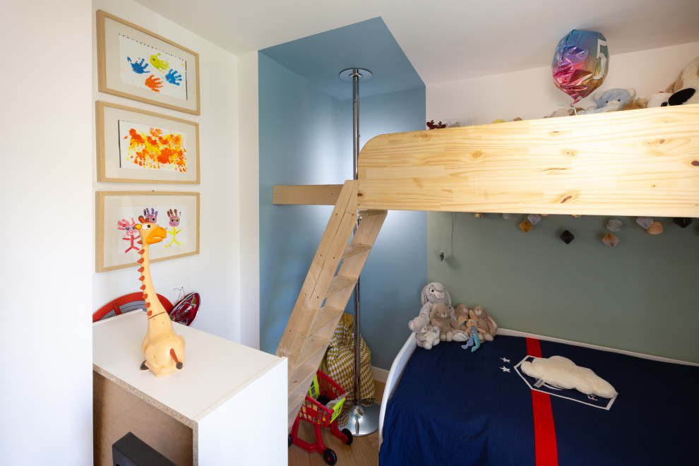 Esempio di una cameretta per bambini da 1 a 3 anni moderna di medie dimensioni con pareti blu, pavimento in compensato, pavimento beige e soffitto ribassato