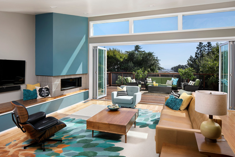 Photo of a midcentury open concept family room in San Francisco with grey walls, light hardwood floors, a ribbon fireplace and a wall-mounted tv.