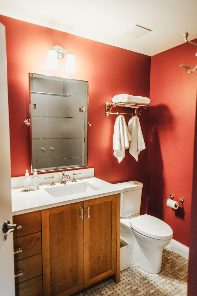 This is an example of a medium sized traditional shower room bathroom in Minneapolis with a built in vanity unit, recessed-panel cabinets, medium wood cabinets, an alcove shower, a two-piece toilet, beige tiles, ceramic tiles, orange walls, marble flooring, a submerged sink, engineered stone worktops, beige floors, a hinged door, white worktops and a single sink.