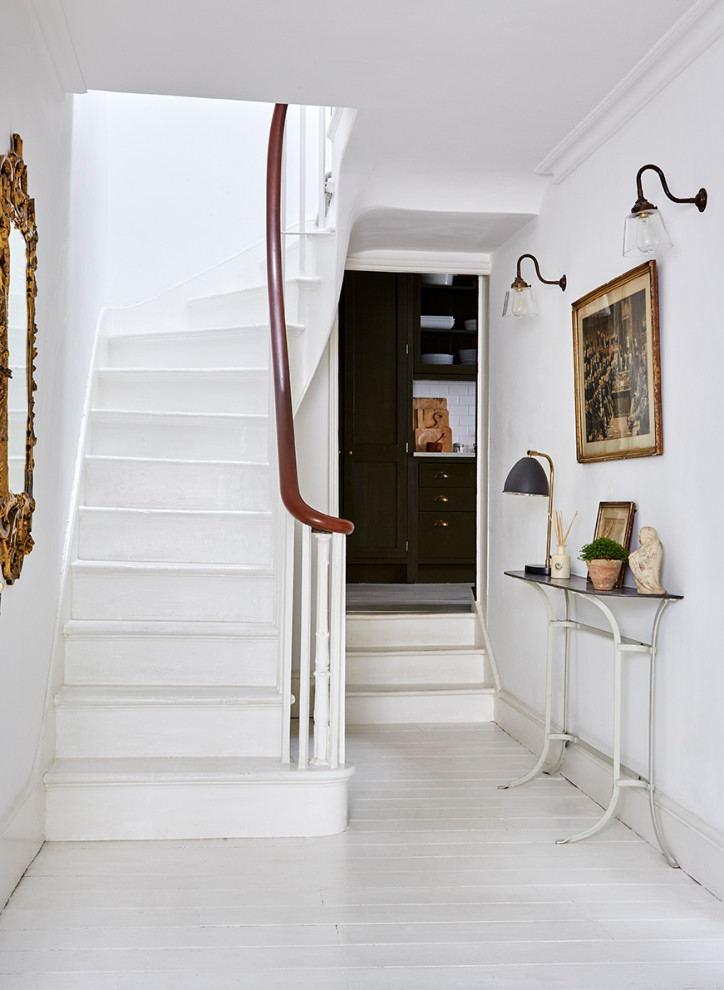 Photo of a transitional painted wood curved staircase in London with painted wood risers and wood railing.