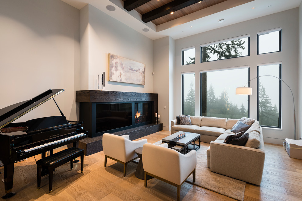 Inspiration for a large transitional open concept living room in Vancouver with white walls, light hardwood floors, a standard fireplace, a wood fireplace surround, a built-in media wall and beige floor.
