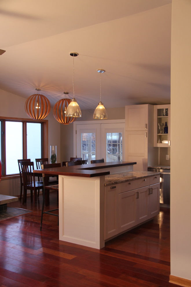Eat-in kitchen - large contemporary l-shaped medium tone wood floor eat-in kitchen idea with a farmhouse sink, recessed-panel cabinets, white cabinets, granite countertops, brown backsplash, glass tile backsplash and stainless steel appliances